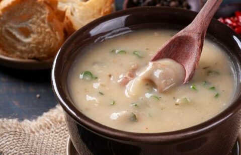 sopa de mandioca servida em pote redondo de cor escura