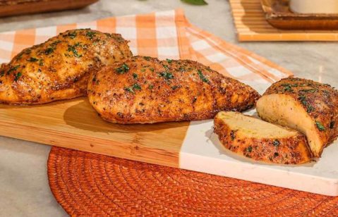 Filés de frango temperados servidos em tábua de madeira.