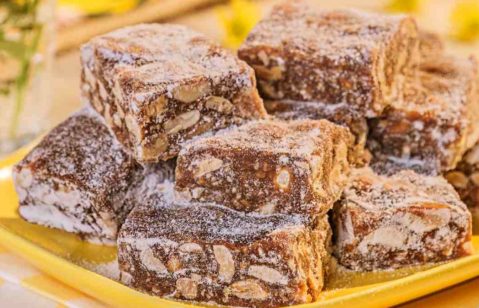 Doces de brigadeiro e amendoim passados no açúcar servidos em um prato retangular amarelo.