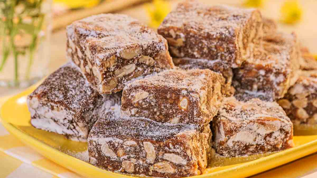 Doces de brigadeiro e amendoim passados no açúcar servidos em um prato retangular amarelo.
