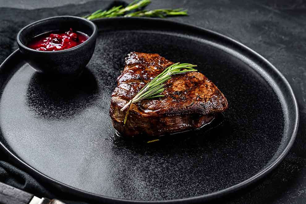 um prato com filé mignon e molho de frutas vermelhas