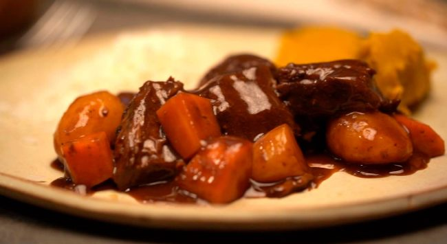 Prato de carne com molho e legumes variados.