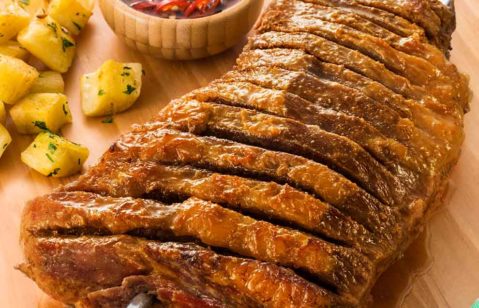 maminha cortada em sanfona bem assada no espeto junto de batatas assadas e um pequeno bowl com molho de pimenta em cima de uma tábua de madeira