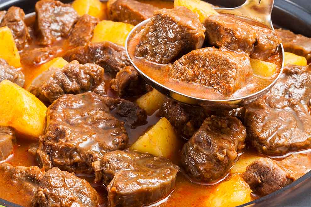 ensopado de carne e batata com uma concha ao lado