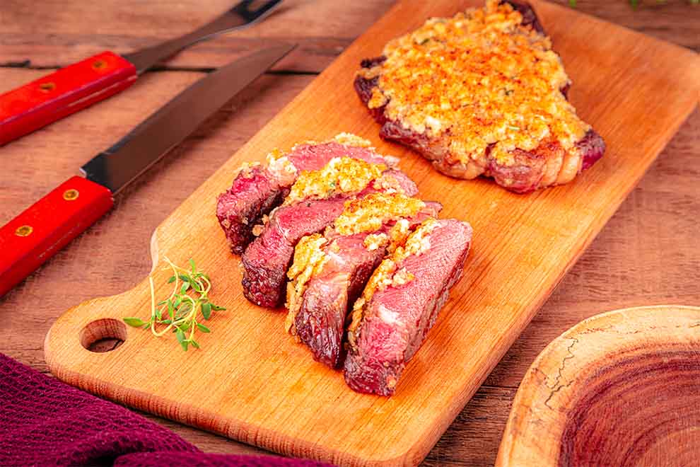 Carne grelhada com crosta dourada em tábua de madeira