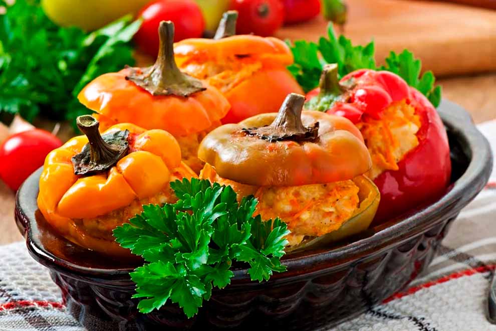 Pimentões recheados coloridos em prato com verduras.