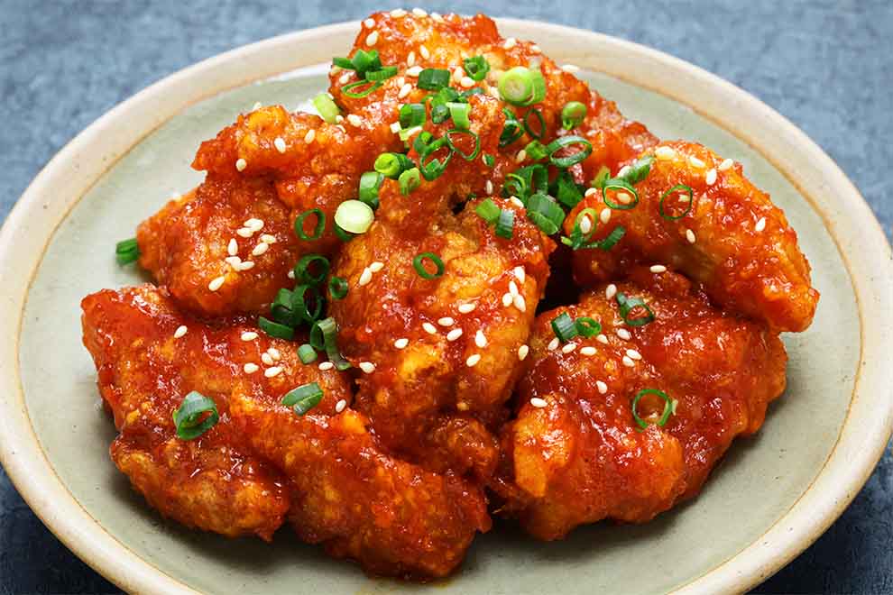 Frango frito crocante com molho picante e cebolinhas.