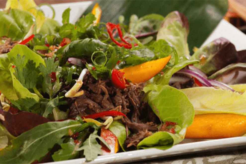 salada thai de músculo bovino dentro de um prato quadrado de porcelana branco