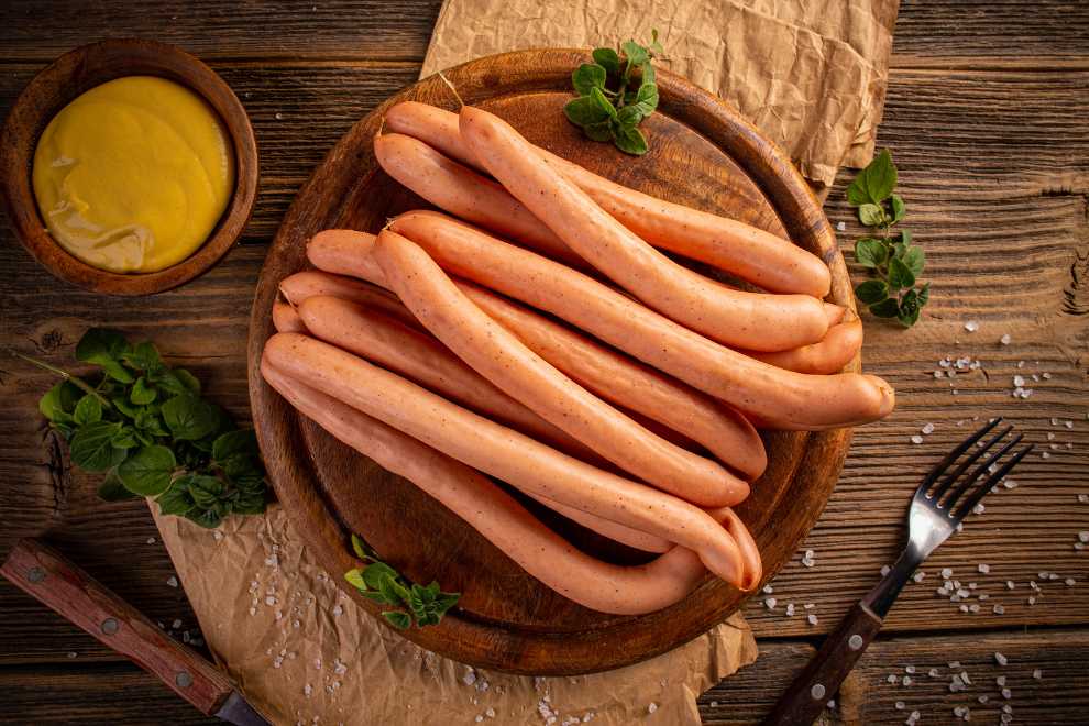salsicha frankfurt em uma tabua de madeira com molho